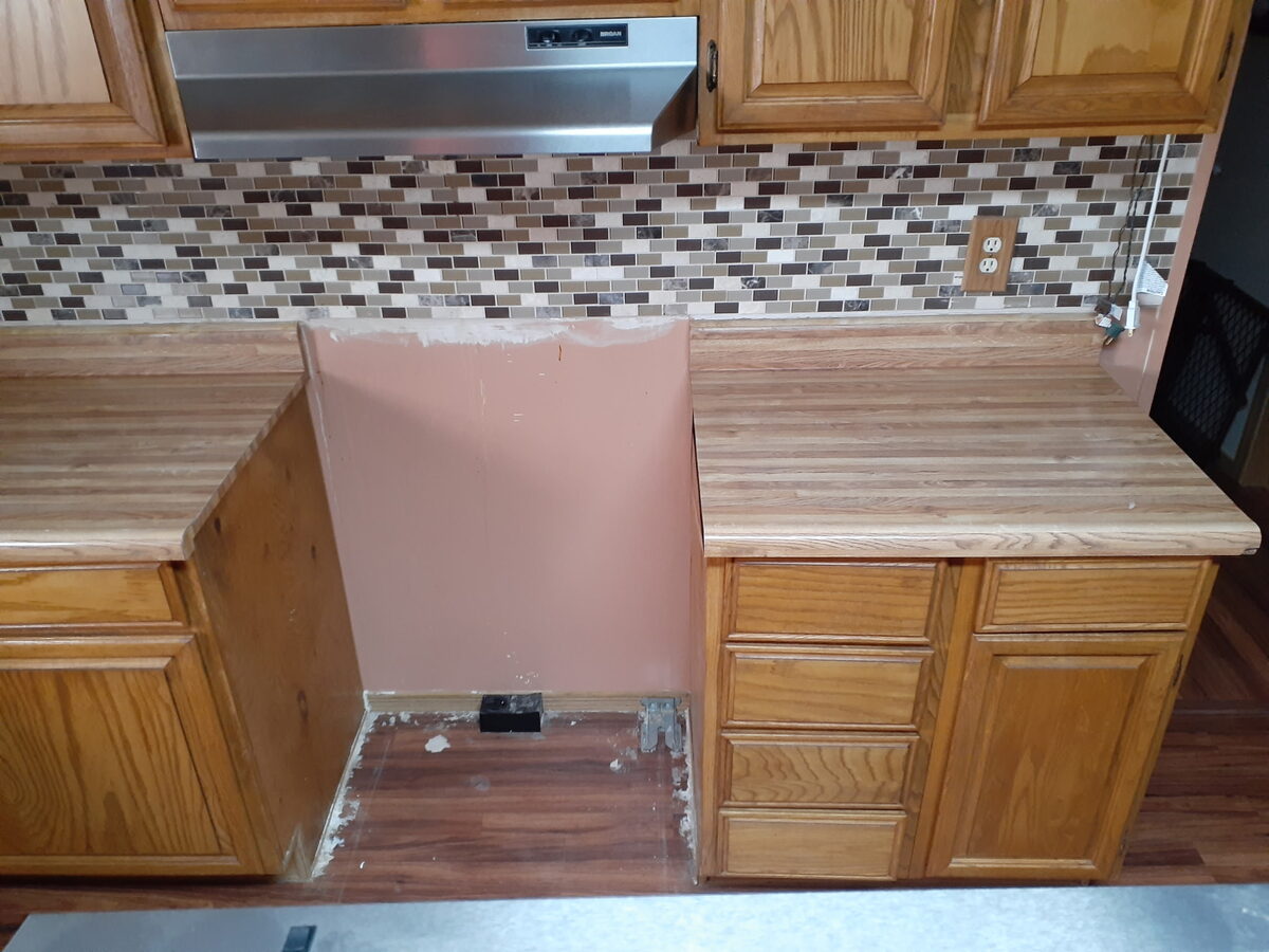 Kitchen countertop before resurfacing — dated wood-laminate countertop with oak cabinets